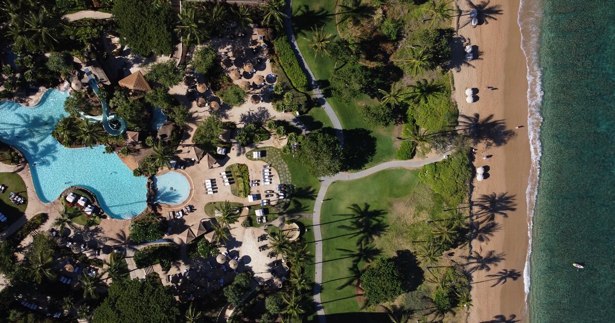 Vista aérea de um resort à beira-mar, com piscinas, jardins e acesso à praia em Kaanapali, Havaí.